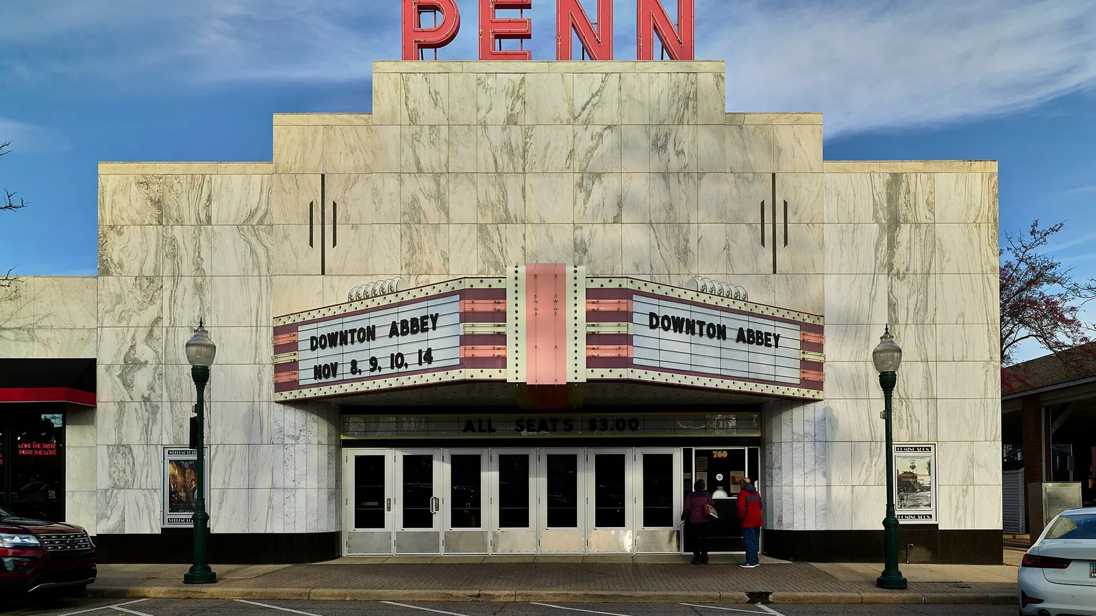 Downtown Plymouth, MI showing Kellogg Park and the historic Penn Theatre marquee with shops and outdoor seating along Main Street