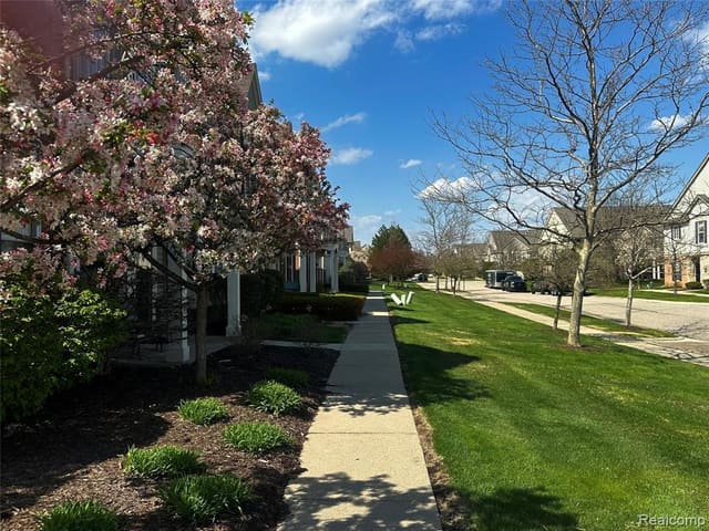 Rear and side view of the condominium with lawn and mature trees