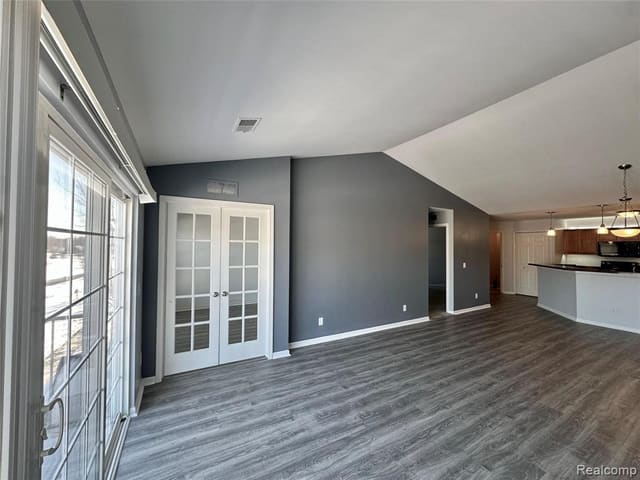 Great room with cathedral ceiling open to the kitchen and balcony doors